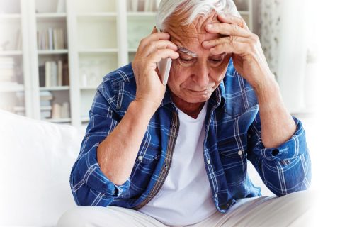 Tensed senior man talking on mobile phone