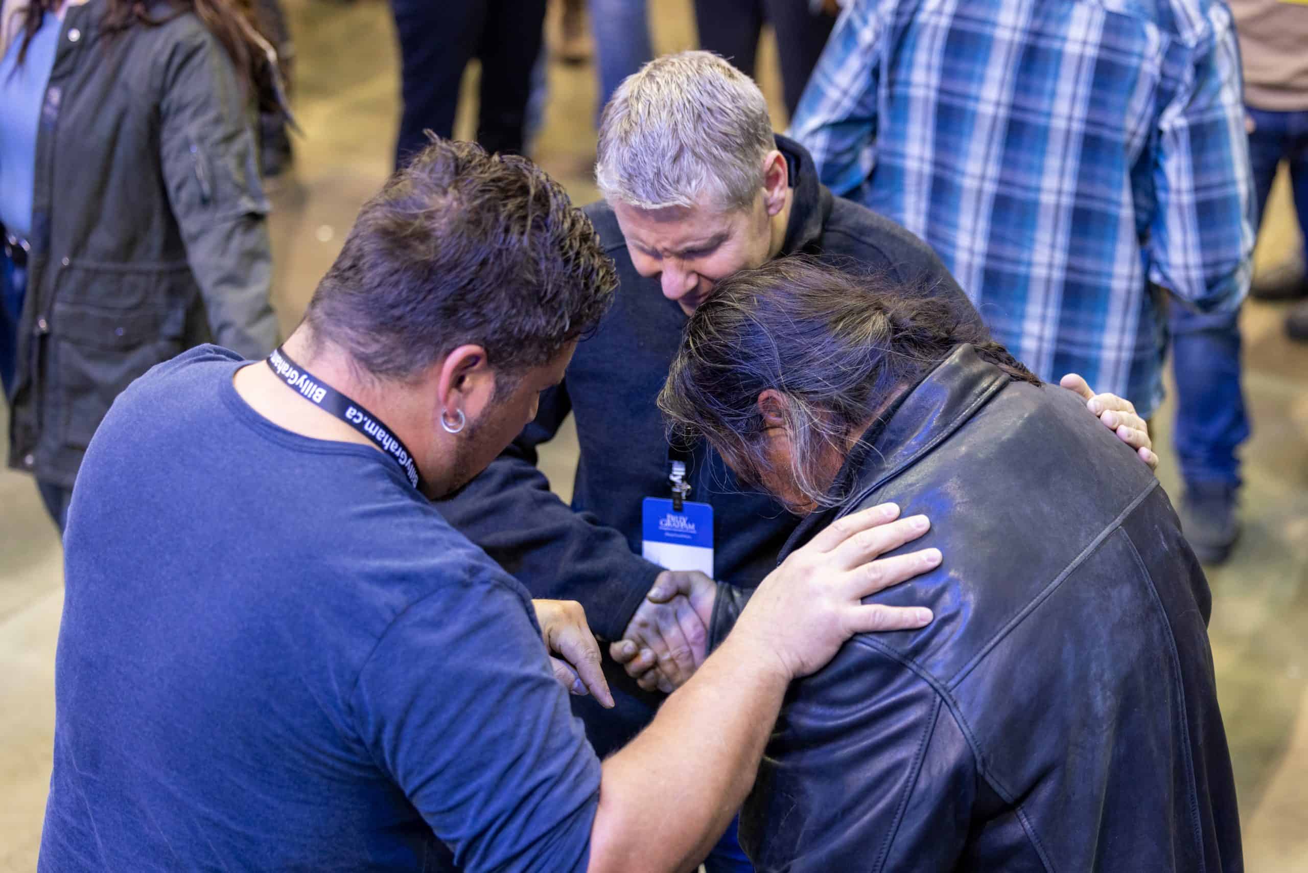 Team members pray with a man who walked forward at Will Graham's Gospel invitation. Those who responded received a free Bible and will be connected with a local church where they can grow in their new faith.